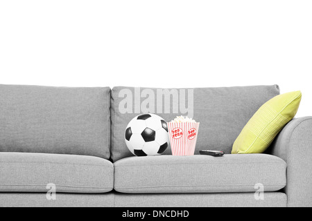 Soccer Ball And Box Of Popcorn On Comfortable Sofa Indoors Stock