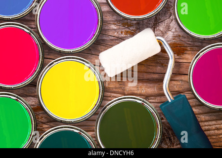 Small paint roller and color tin cans on old wood background. Redecoration and renovation concept. Stock Photo