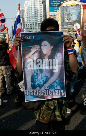 Bangkok, Thailand. December 22nd, 2013. an anti-government protester hides behind a doctored, degrading and misleading poster of Yingluck Shinawatra, the current Prime Minister of Thailand. Hundreds of thousands of protesters took to the streets to demand the resignation of the Thai Prime Minister. Credit: Kraig Lieb / Alamy Live News Stock Photo