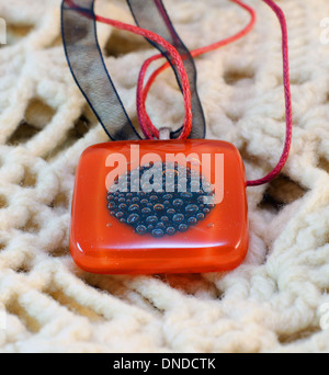 original red glass handmade amulet on knitted background Stock Photo