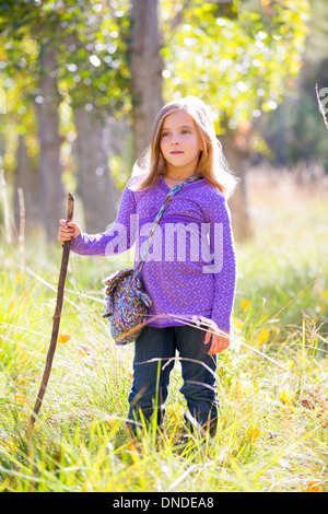 Hiking kid girl with walking stick in autum poplar trees forest Stock Photo