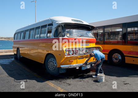 A bus driver washes a vintage Leyland Malta bus in Cirkewwa, Malta. Stock Photo