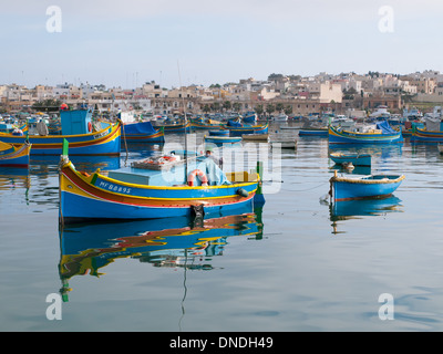 A local, Maltese fisherman in a colourful, luzzu traditional fishing boat in Marsaxlokk Harbour in Marsaxlokk, Malta. Stock Photo