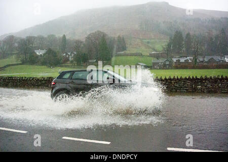 Grasmere, UK. 23rd Dec, 2013. Traffic on the A591 at Grasmere in the English Lake District had to endure floods of water on the road. This stretch of road between Windermere and Keswick has been voted Britain's best drive. Credit:  Wayne HUTCHINSON/Alamy Live News Stock Photo