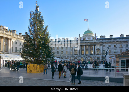 Historical Somerset House courtyard with Christmas tree decorations & people enjoying outdoor ice rink skating arena at The Strand London England UK Stock Photo