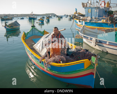 A local Maltese fisherman in a luzzu in Marsaxlokk Harbour, Malta. Stock Photo