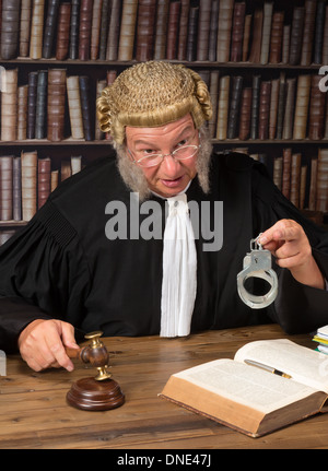 Old judge with authentic wig in courtroom holding handcuffs Stock Photo