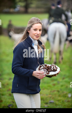 A young huntswoman handing out Christmas cake with the traditional stirrup cup at a meeting of the Beaufort Hunt in Didmarton UK Stock Photo