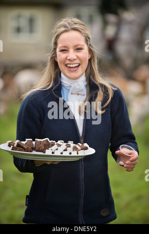 A young huntswoman handing out Christmas cake with the traditional stirrup cup at a meeting of the Beaufort Hunt in Didmarton UK Stock Photo