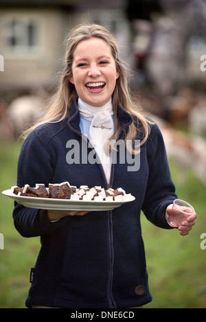 A young huntswoman handing out Christmas cake with the traditional stirrup cup at a meeting of the Beaufort Hunt in Didmarton UK Stock Photo