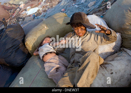 Young child laborers are playing on sacks filled with garbage at the Stung Meanchey Landfill in Phnom Penh, Cambodia. Stock Photo