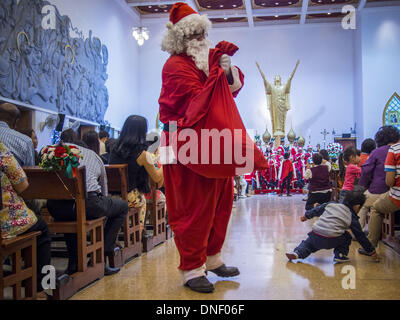 Bangkok, Thailand. 24th Dec, 2013. Santa Claud delivers candy to parishioners during Christmas services at Holy Redeemer Church in Bangkok. Thailand is predominantly Buddhist but Christmas is widely celebrated throughout the country. Buddhists mark the day with secular gift giving but there are about 300,000 Catholics in Thailand who celebrate religious Christmas. Catholics first came to Thailand (then Siam) in 1567 as chaplain for Portuguese mercenaries in the employ of the Siamese monarchy. Credit:  ZUMA Press, Inc./Alamy Live News Stock Photo