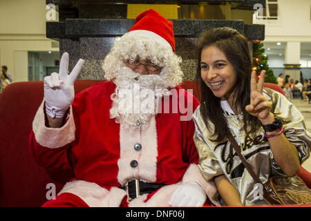 Bangkok, Thailand. 24th Dec, 2013. A Thai woman poses with Santa Claus during Christmas observances at Holy Redeemer Church in Bangkok. Thailand is predominantly Buddhist but Christmas is widely celebrated throughout the country. Buddhists mark the day with secular gift giving but there are about 300,000 Catholics in Thailand who celebrate religious Christmas. Catholics first came to Thailand (then Siam) in 1567 as chaplain for Portuguese mercenaries in the employ of the Siamese monarchy. Credit:  ZUMA Press, Inc./Alamy Live News Stock Photo