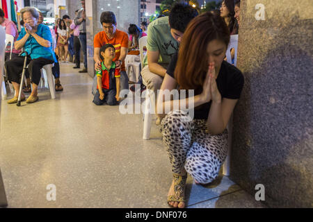 Bangkok, Thailand. 24th Dec, 2013. People pray outside the church during Christmas services at Holy Redeemer Church in Bangkok. Thailand is predominantly Buddhist but Christmas is widely celebrated throughout the country. Buddhists mark the day with secular gift giving but there are about 300,000 Catholics in Thailand who celebrate religious Christmas. Catholics first came to Thailand (then Siam) in 1567 as chaplain for Portuguese mercenaries in the employ of the Siamese monarchy.  © Jack Kurtz/ZUMAPRESS. Credit:  ZUMA Press, Inc./Alamy Live News Stock Photo