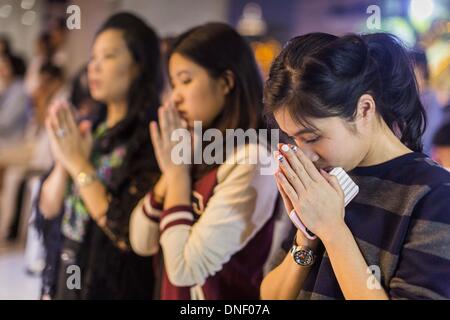 Bangkok, Thailand. 24th Dec, 2013. People pray outside the church during Christmas services at Holy Redeemer Church in Bangkok. Thailand is predominantly Buddhist but Christmas is widely celebrated throughout the country. Buddhists mark the day with secular gift giving but there are about 300,000 Catholics in Thailand who celebrate religious Christmas. Catholics first came to Thailand (then Siam) in 1567 as chaplain for Portuguese mercenaries in the employ of the Siamese monarchy.  © Jack Kurtz/ZUMAPRESS. Credit:  ZUMA Press, Inc./Alamy Live News Stock Photo