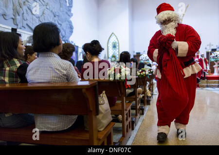 Bangkok, Thailand. 24th Dec, 2013. Santa Claud delivers candy to parishioners during Christmas services at Holy Redeemer Church in Bangkok. Thailand is predominantly Buddhist but Christmas is widely celebrated throughout the country. Buddhists mark the day with secular gift giving but there are about 300,000 Catholics in Thailand who celebrate religious Christmas. Catholics first came to Thailand (then Siam) in 1567 as chaplain for Portuguese mercenaries in the employ of the Siamese monarchy. Credit:  ZUMA Press, Inc./Alamy Live News Stock Photo