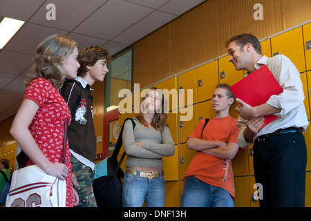 Group of teenager boys and girls talking in the schoolhall with their teacher Stock Photo