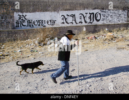 An elderly man walks his dog past a gang marker in memory of a slain member along a street corner where ten people have been killed in drug crimes January 22, 2009 in Juarez, Mexico. The ongoing drug war has already claimed more than 40 people since the start of the year. More than 1600 people were killed in Juarez in 2008, making Juarez the most violent city in Mexico. Stock Photo