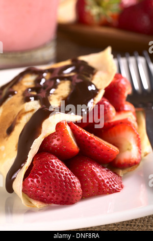 Crepe filled with fresh strawberries and chocolate sauce on top (Selective Focus, Focus on the strawberry in the front) Stock Photo
