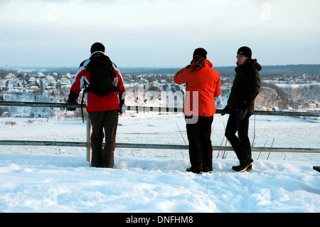 Three people looking out across the frozen St Lawrence river in Quebec City Stock Photo