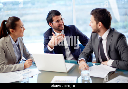 Portrait of three co-workers discussing business plan in office Stock Photo
