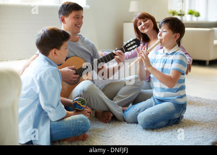 Portrait of handsome siblings and their father playing musical instruments at home Stock Photo