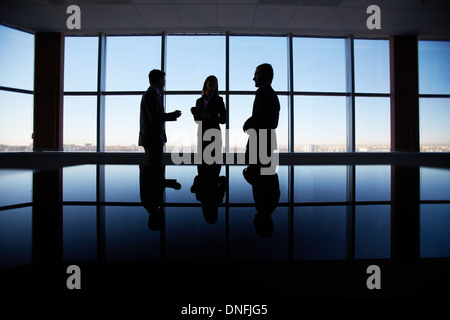 Outlines of three office workers interacting by the window Stock Photo