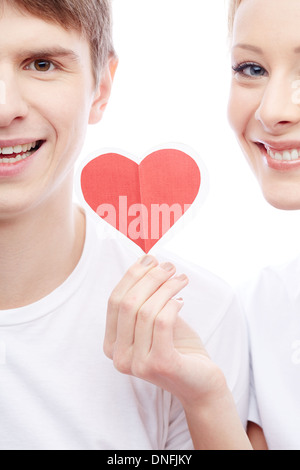 Portrait of happy couple looking at camera while girl holding red paper heart