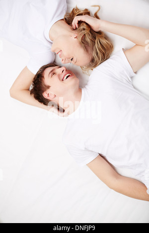Two happy young dates lying in bed and laughing Stock Photo