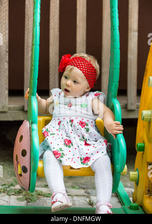 year-old adorable little child girl sitting on a swing at summer,Almaty, Kazakhstan Stock Photo