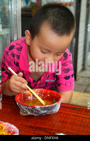 Beijing China,Asia,Chinese,Oriental,Xicheng,Asian Asians,boy boys lad lads male kid kids child children,eating,chopsticks,food,soup,visitors travel tr Stock Photo