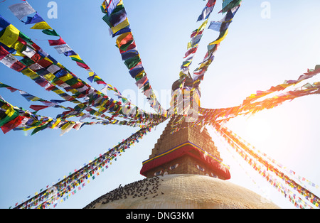 Prayer flags flying against the sun from the Boudhanath Stupa - symbol Kathmandu, Nepal. Stock Photo