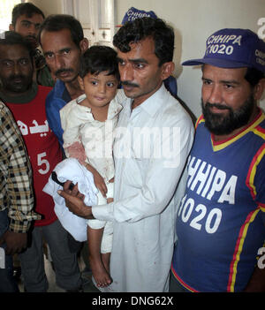 Karachi, Pakistan. 27th Dec, 2013. Father of seven years old girl, Uzma who killed in hand grenade attack on a house situated in P.E.C.H.S block 02, standing with his injured boy at Jinnah Hospital Mortuary in Karachi on Friday, December 27, 2013. The house is the property of a trader and according to police extortion mafia attacked on house caused a girl dead and a boy injured. Credit:  Asianet-Pakistan/Ģ����ý Live News Stock Photo