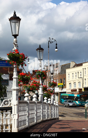 View along High Street, railings of bridge over River Medway and geraniums in hanging baskets on street lamps in foreground, Tonbridge, Kent, England Stock Photo