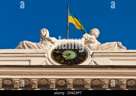 Fragment of a facade of a building of Odessa city council - chiming clock, sculptural composition and a national flag of Ukraine Stock Photo