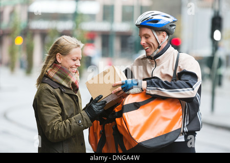 Young Woman Receiving A Package From Courier Delivery Man Stock Photo
