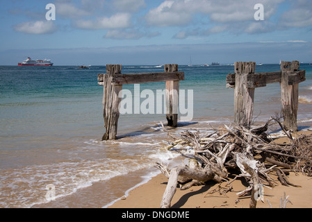 old ruins of a pier on the  Victorian coast shore spirit of tasmania ferry on the ocean with the drift wood and old pier in fore Stock Photo