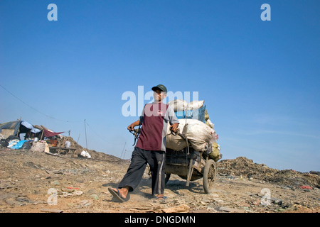 A man is pulling a heavy cart filled with sacks at the toxic Stung Meanchey Landfill in Phnom Penh, Cambodia. Stock Photo