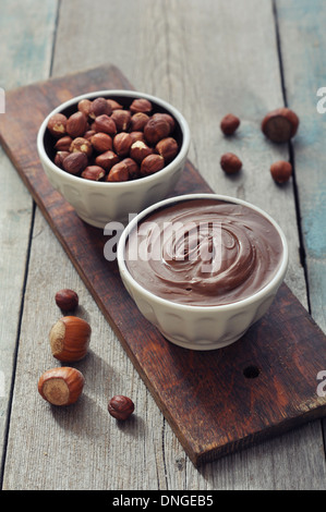 Hazelnut cream in ceramic bowl with hazelnut nuts on wooden background Stock Photo