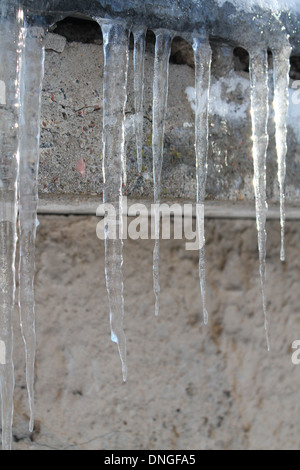 big crystal icicles on the edge of the roof Stock Photo