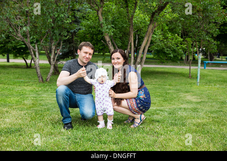 Happy family: mother, father and daughter baby playing in the park Stock Photo