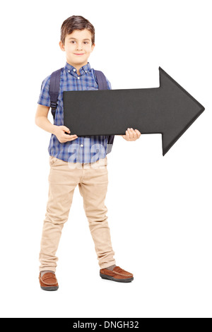 Full length portrait of a boy with school bag holding a big black arrow pointing right, Stock Photo