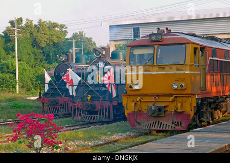 Modern diesel train alongside two veteran locomotives from WW2 at Kanchanaburi Stock Photo