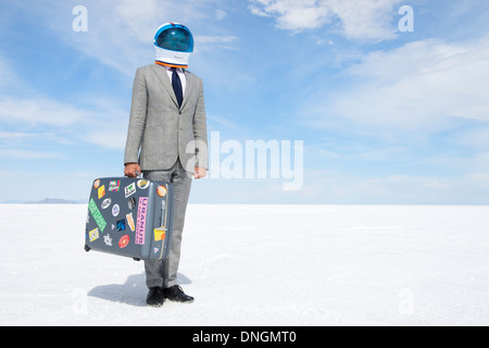 Space tourist businessman astronaut traveling with suitcase on aerospace voyage to dramatic other worldly lunar landscape Stock Photo