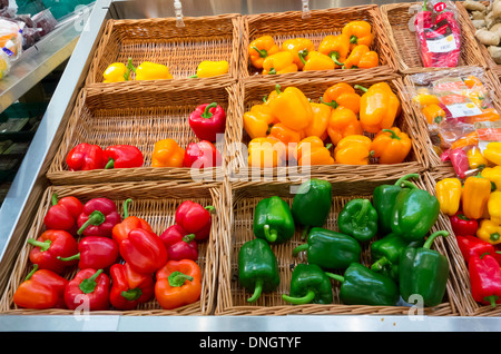 A supermarket display of small red yellow and green peppers in baskets. Stock Photo