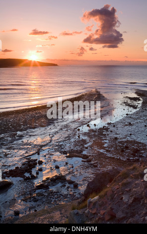 A cloud in the shape of a number 2 floats across Runswick Bay at sunset looking from Kettleness, North Yorkshire. Stock Photo