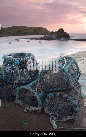 Lobster pots stacked up at the harbour in Hope Cove, Devon, England, at sunset. Stock Photo
