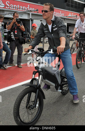 FILE: Silverstone, UK. 8th July, 2010. German Formula One race driver Michael Shumacher from the team Mercedes GP drives with an electric bicycle through the pit lane in Silverstone, England, 8 July 2010. This weekend, the British grand prix starts with the tenth race of the Formula One season 2010. Photo: Carmen Jaspersen/dpa/Alamy Live News Stock Photo