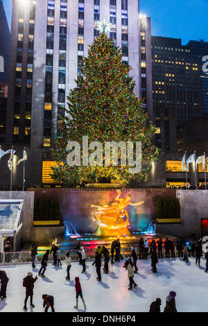 Rockefeller Plaza, New York, with skaters enjoying skating on ice rink with illuminated Christmas tree lights, at dusk Stock Photo