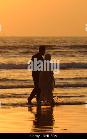 Karachi, Pakistan. 30th Dec, 2013. A couple walks on the Clifton beach during sunset in southern Pakistani port city of Karachi, Dec. 29, 2013. Credit:  Ahmad Kamal/Xinhua/Alamy Live News Stock Photo